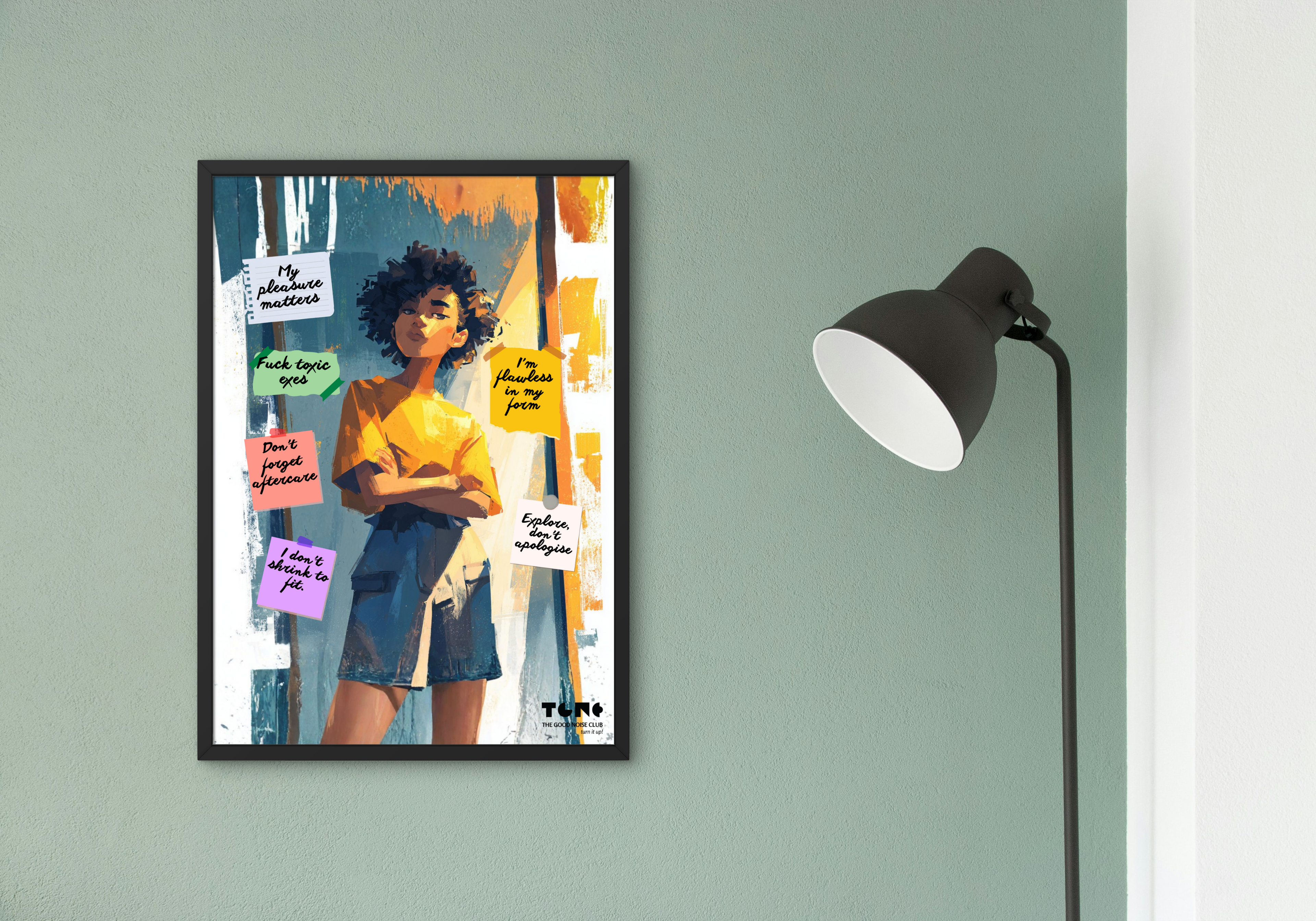 Framed artwork of a person with colorful text on a wall next to a lamp.