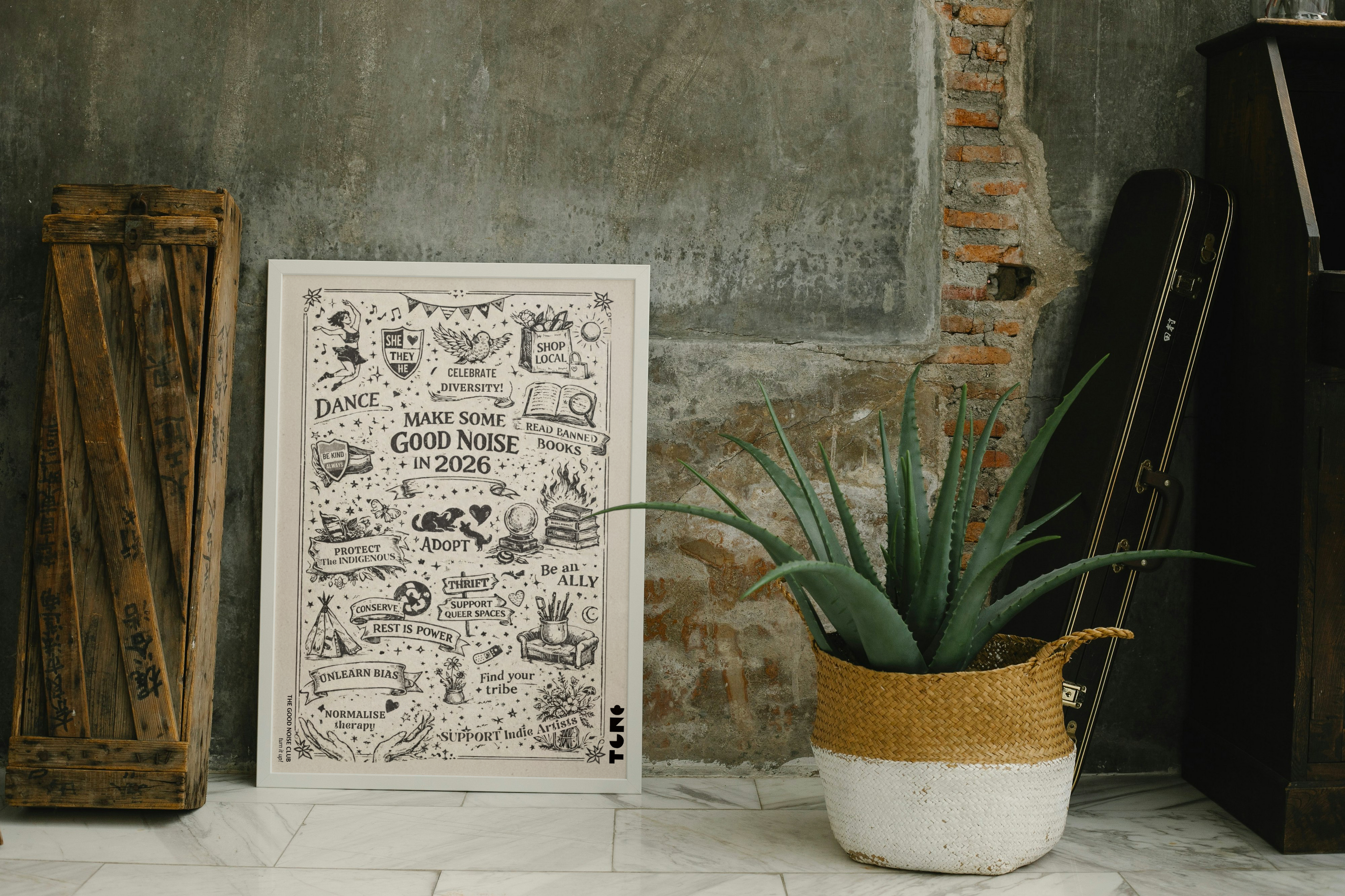 Decorative poster with text and illustrations on a wall next to a plant and wooden crate.
