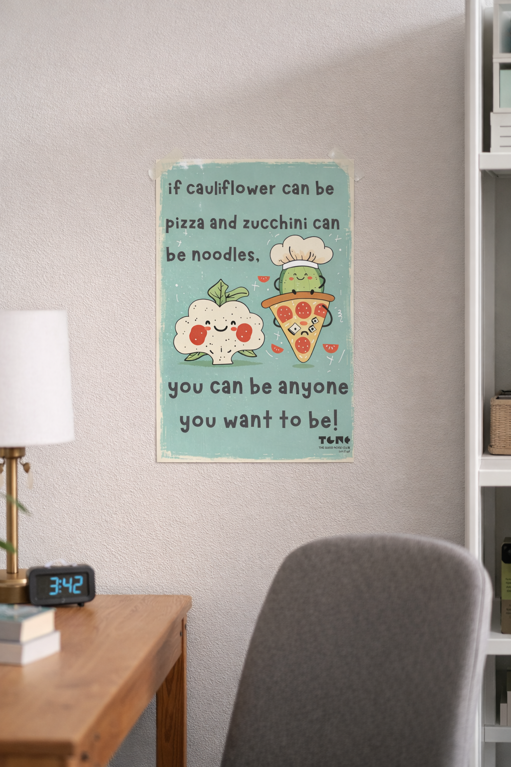 Motivational poster on a wall above a desk with a lamp and clock.