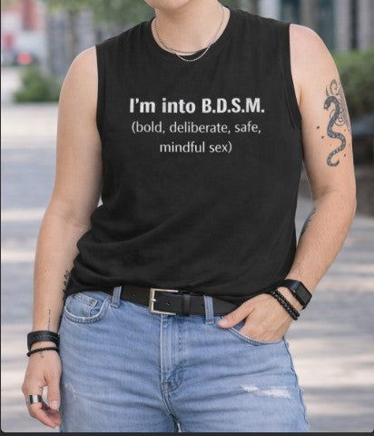Person wearing a black sleeveless shirt with BDSM definition text outdoors.