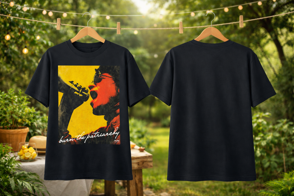 Black t-shirt with graphic design and text 'burn the patriarchy' on a hanger against a natural background.