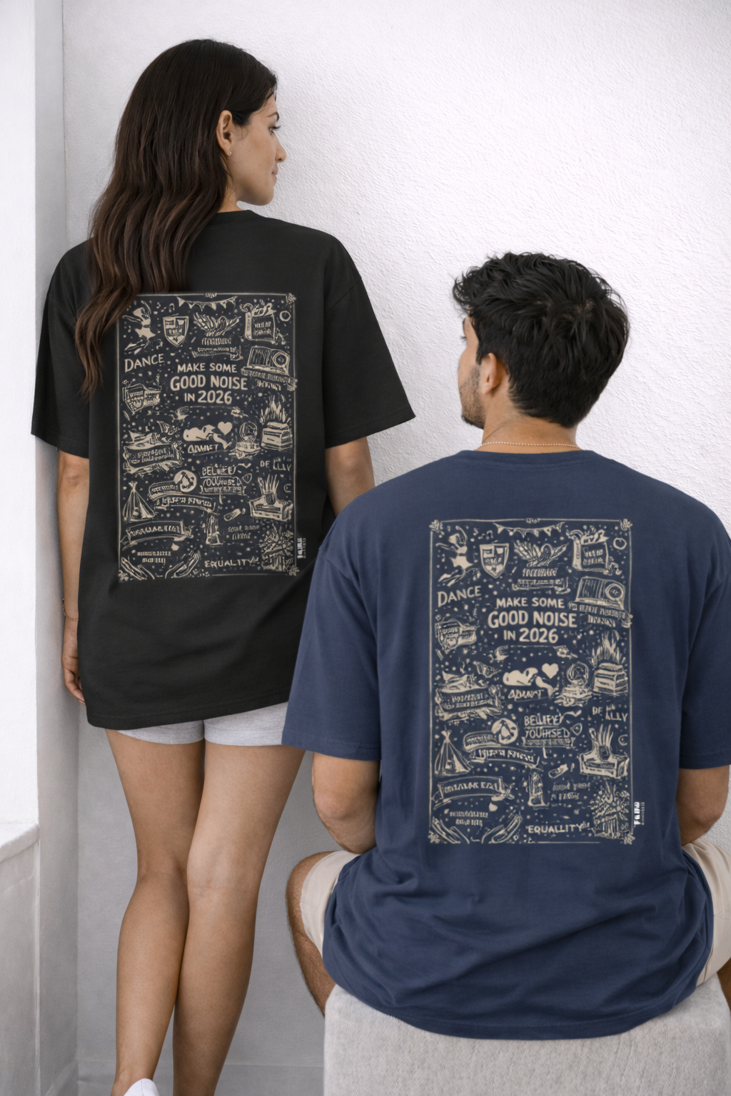 Two people wearing t-shirts with a patterned design on the back, standing against a white wall.