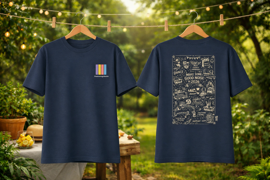 Two navy blue t-shirts with designs on hangers against a garden background.