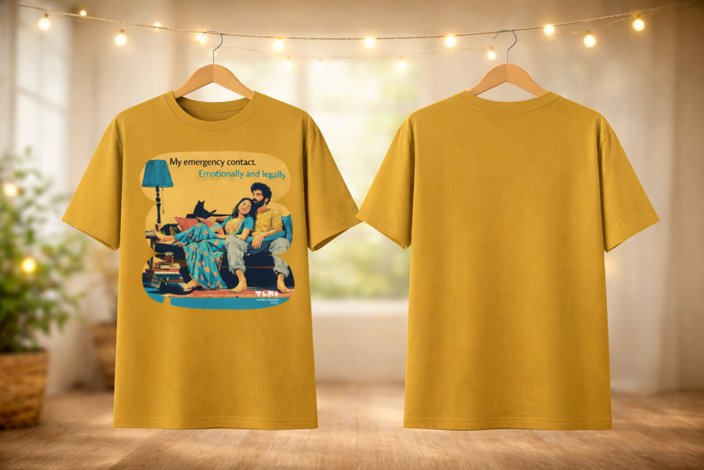 Yellow t-shirt with a graphic design on a wooden floor with string lights in the background