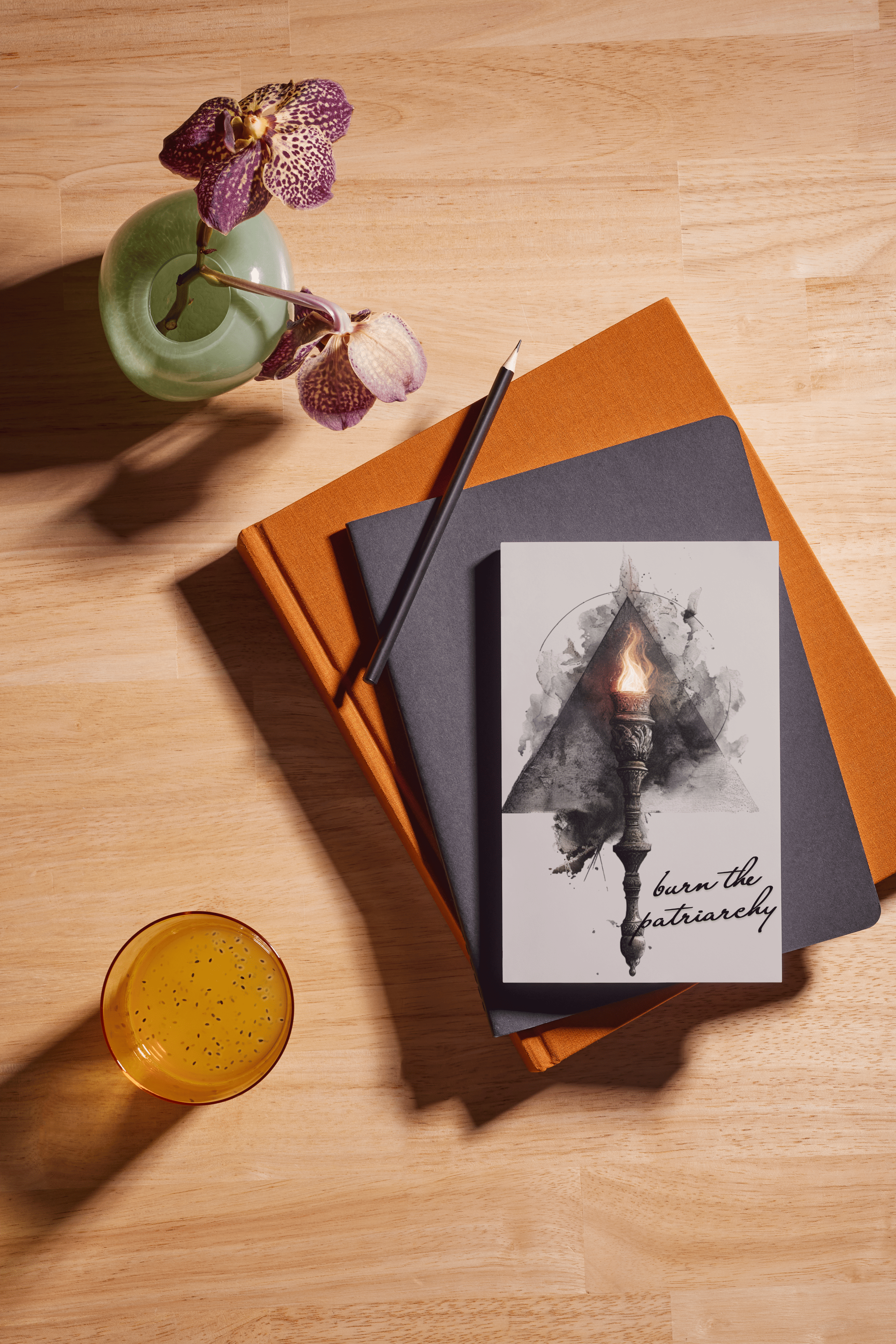 Stack of books with a candle illustration, a pen, and a drink on a wooden surface.