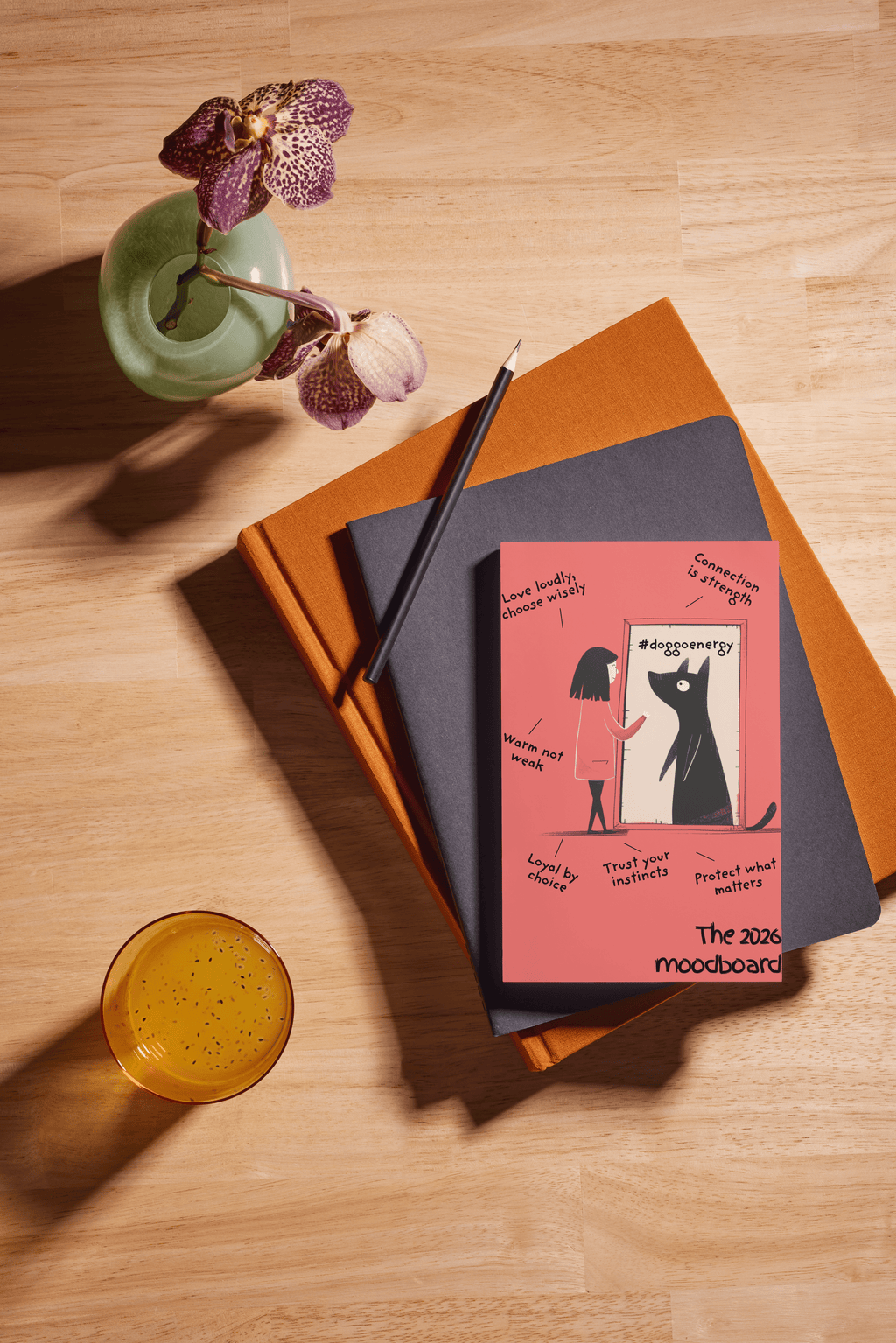 Notebooks and a pink book with a cat illustration on a wooden surface.