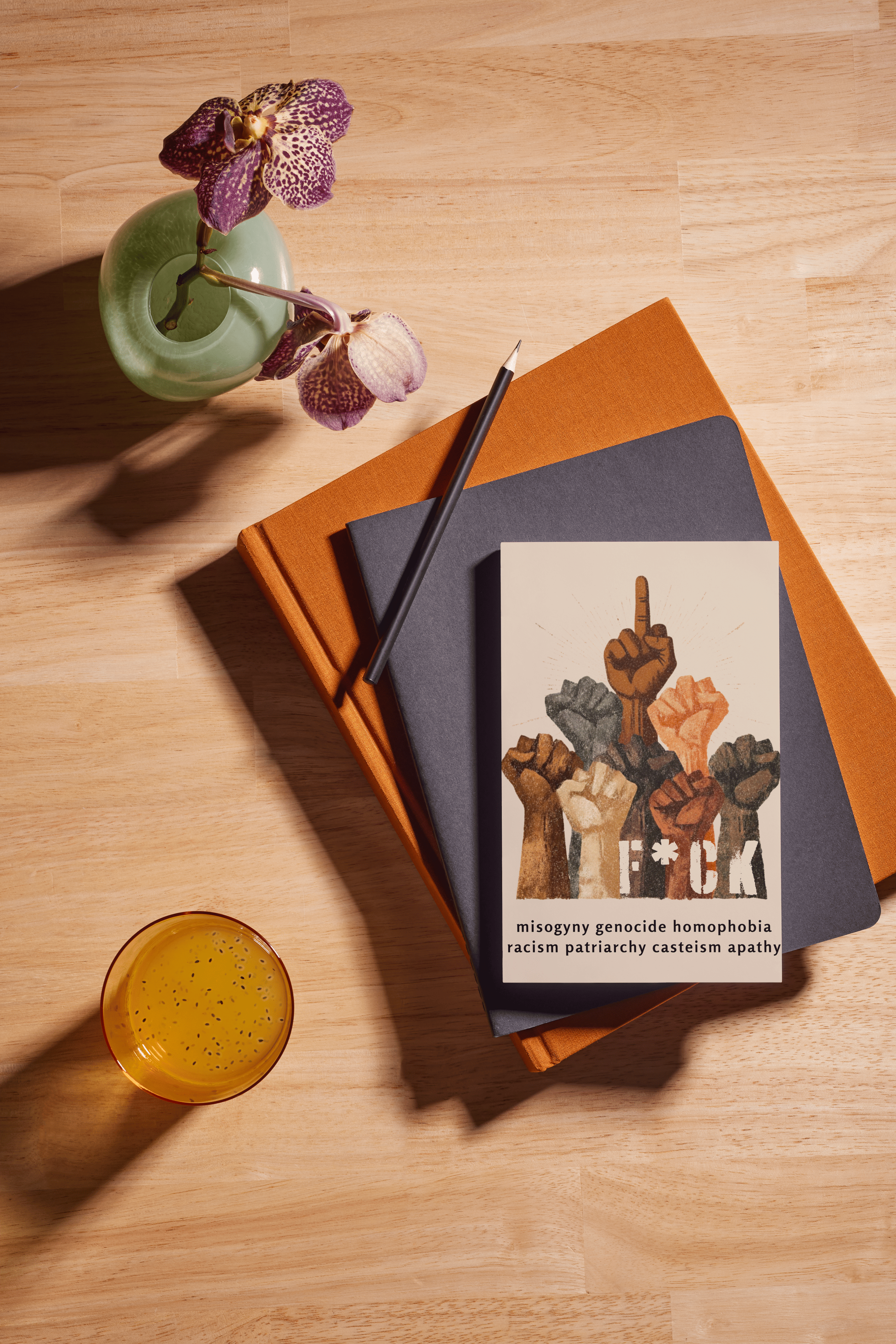 Book with a graphic design on a wooden surface with a drink and flowers.