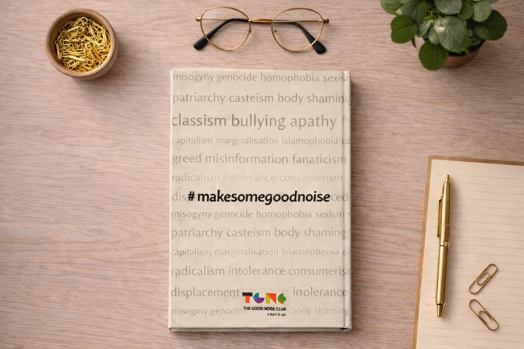 Book titled 'TUNA' on a wooden surface with glasses, paper clips, and a plant.